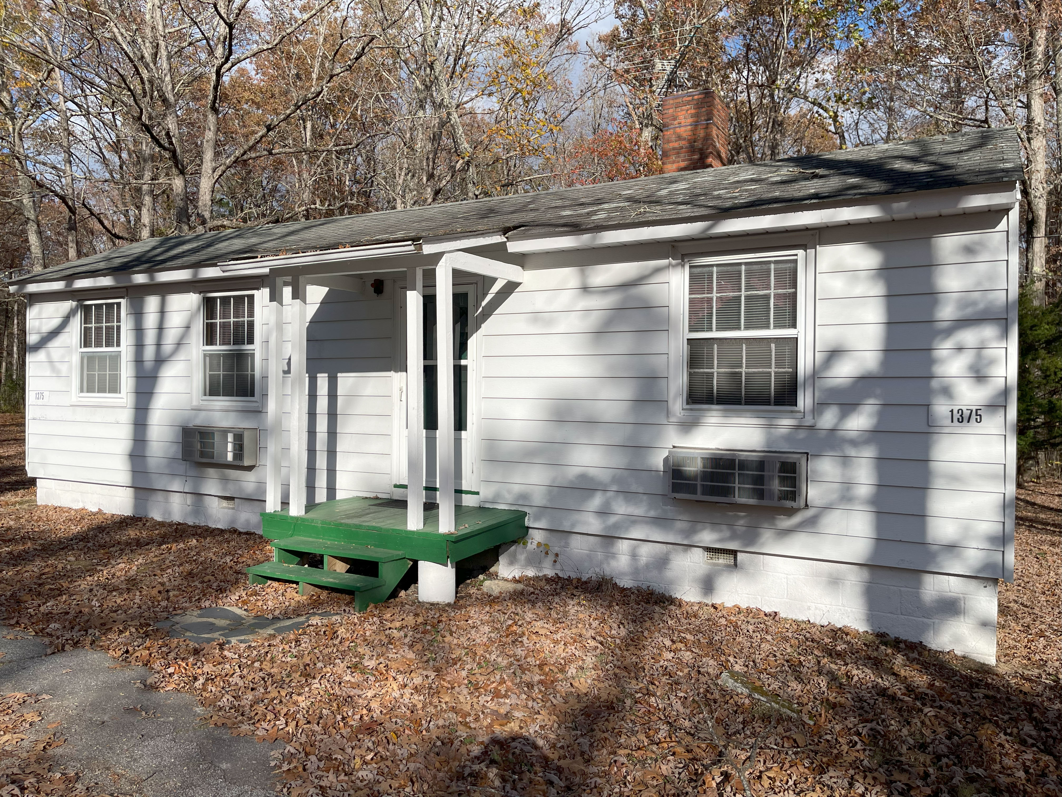 white one story home with air conditioning units and green steps